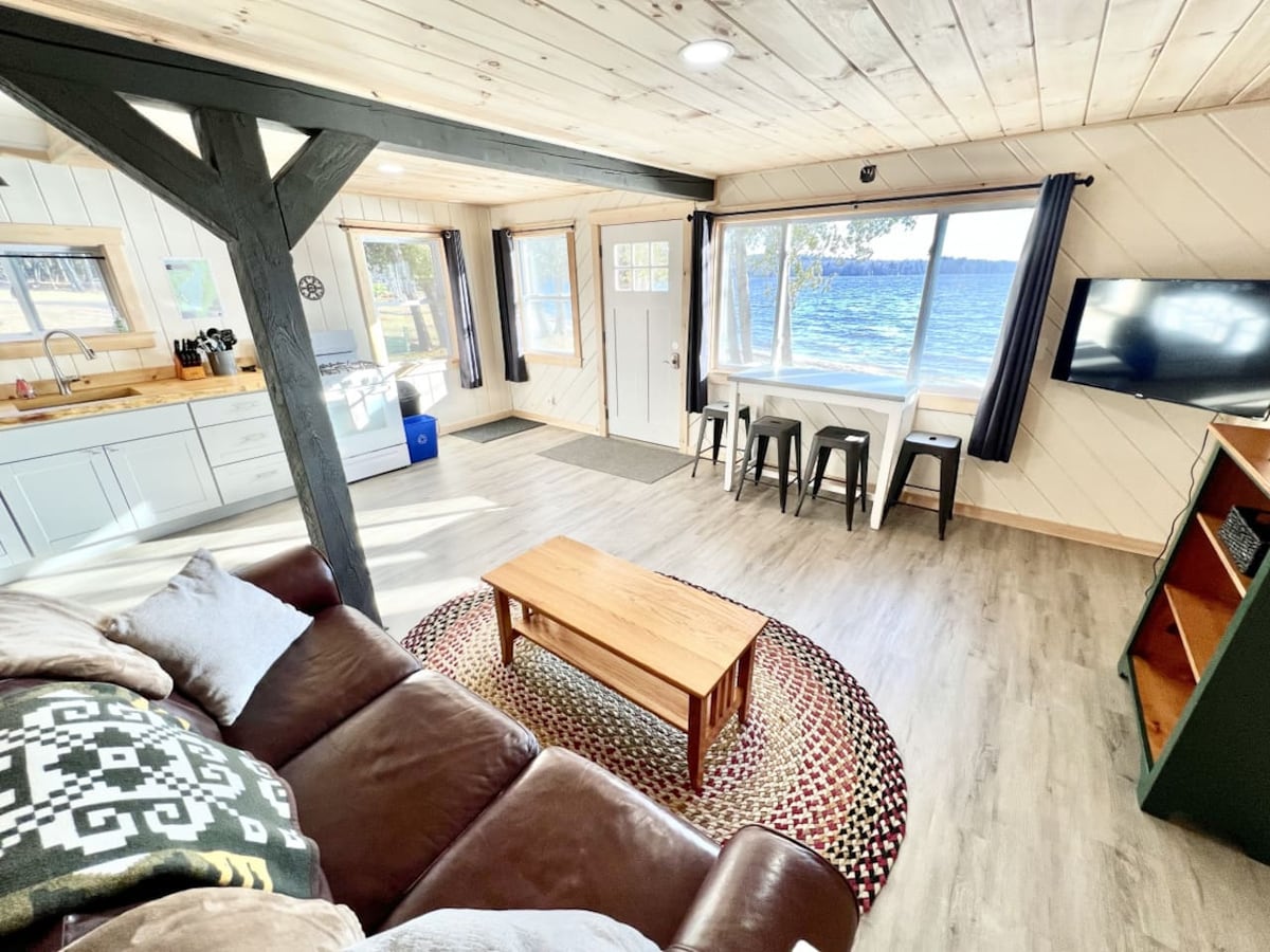 A comfortable cabin living room with a couch, Roku TV, games, kitchen, and lake views